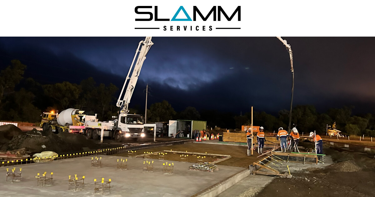 Nighttime construction with concrete pump, highlighting Slamm Services' civil and construction expertise.